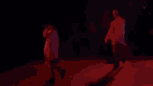 a man in a red jacket is walking on a stage