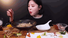 a woman is eating noodles with chopsticks from a bowl .