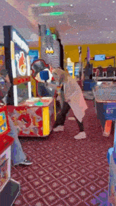 a woman is playing a game in an amusement park while a man watches .
