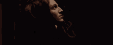 a woman with long hair is looking up in the dark .