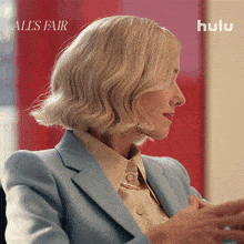 a woman in a blue suit is sitting in front of a hulu ad