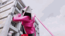 a pink power ranger is standing in front of a tall building