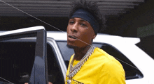a man wearing a headband and a yellow shirt is getting out of a white suv