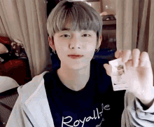 a young man is holding a card in his hand and wearing a hoodie .