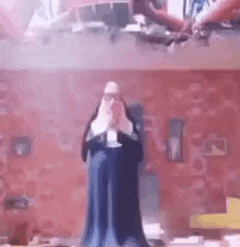 a statue of a nun is standing in front of a brick wall in a room .
