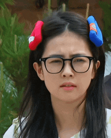 a woman wearing glasses and a red and blue headband has a serious look on her face