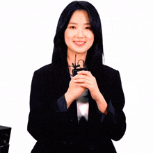 a woman in a black suit is holding a microphone in her hands