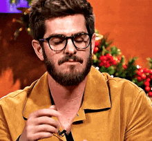 a man with a beard is wearing glasses and a yellow jacket