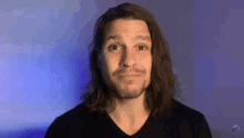 a man with long hair and a beard is wearing a black t-shirt