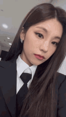 a woman in a suit and tie is taking a selfie