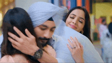 a man in a turban is hugging a woman in a pink dress .