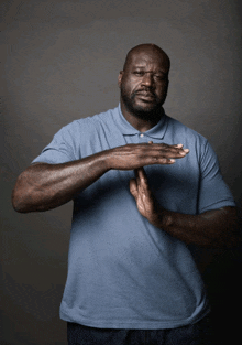a man in a blue shirt is making a stop gesture with his hands