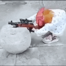 a person is holding a gun next to a snowball on the sidewalk .