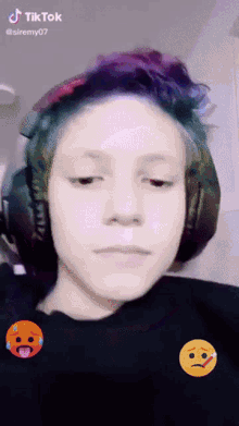 a girl with headphones and a smiley face on her shirt says tiktok