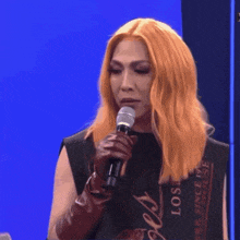 a woman with red hair is holding a microphone and wearing a black shirt that says lost