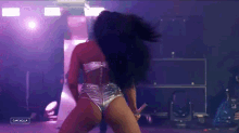 a woman in silver shorts is dancing on a stage in front of a sign that says campbella