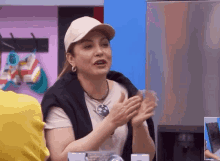 a woman wearing a white hat and a black sweater is clapping her hands