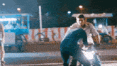 a man riding a motorcycle is talking to another man