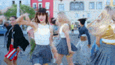 a group of women are dancing in front of a building that says 00 on it