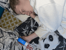 a person is laying on a bed with a panda blanket