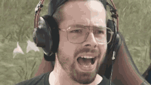 a man with a beard wearing headphones and glasses is making a funny face .