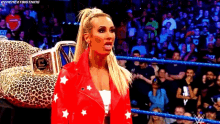 a woman in a red jacket is standing in a wrestling ring with a leopard print car in the background .
