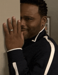 a man with a ring on his finger is peeking over a wall