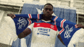 a man wearing a unibet shirt holds a blue and white scarf