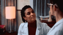 a woman in a lab coat talks to another woman in a room