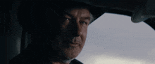 a man wearing a cowboy hat is smiling while sitting in the driver 's seat of a car