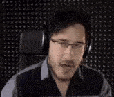 a man wearing headphones is sitting in a chair with his mouth open .