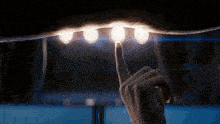 a person 's finger is pointing at a light bulb in the dark