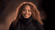 a woman with curly hair is smiling and wearing a black scarf around her neck