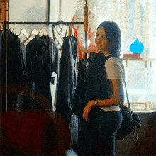 a woman is standing in front of a rack of black clothes