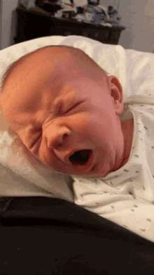 a baby is laying on a pillow with its mouth open