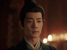 a man with a bun on his head is standing in a dark room with lights .