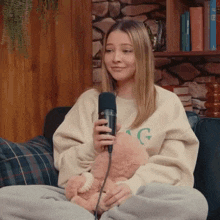 a woman sitting on a couch with a teddy bear and a microphone