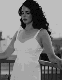 a woman in a white dress is standing next to a railing .