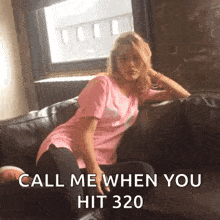 a woman in a pink shirt is sitting on a couch with her legs crossed .