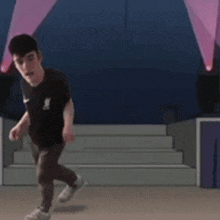 a man in a black nike shirt is dancing on a stage