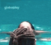 a woman is swimming in a pool with a globeplay logo on the bottom .