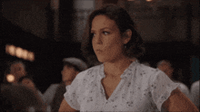 a woman in a white shirt is sitting in a room with other people