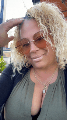 a woman with curly blonde hair wearing sunglasses and a necklace