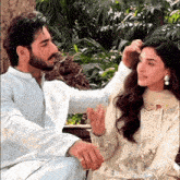 a man is touching a woman 's hair while they sit on a bench