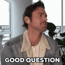 a man wearing a denim jacket and earbuds says good question .