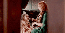 a woman is sitting next to a little girl .