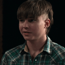 a young man in a plaid shirt looks down