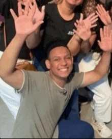a man in a grey shirt is kneeling down with his hands in the air .