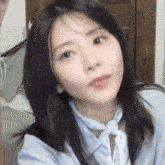a close up of a woman 's face wearing a blue shirt and tie .