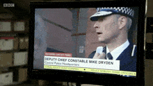 a tv screen shows a news report about deputy chief constable mike dryden from central police headquarters